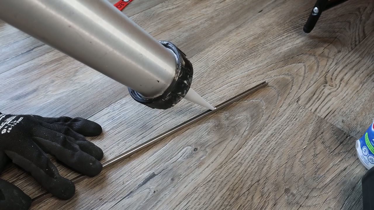 Thin silicone bead running down the inside channel of the stainless track cap