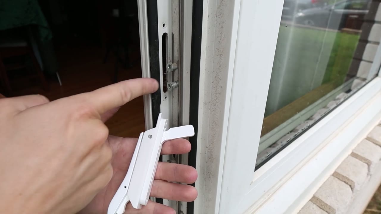 New locking handle at the jamb cutout, finger on the two tie-bar posts its fin slides between